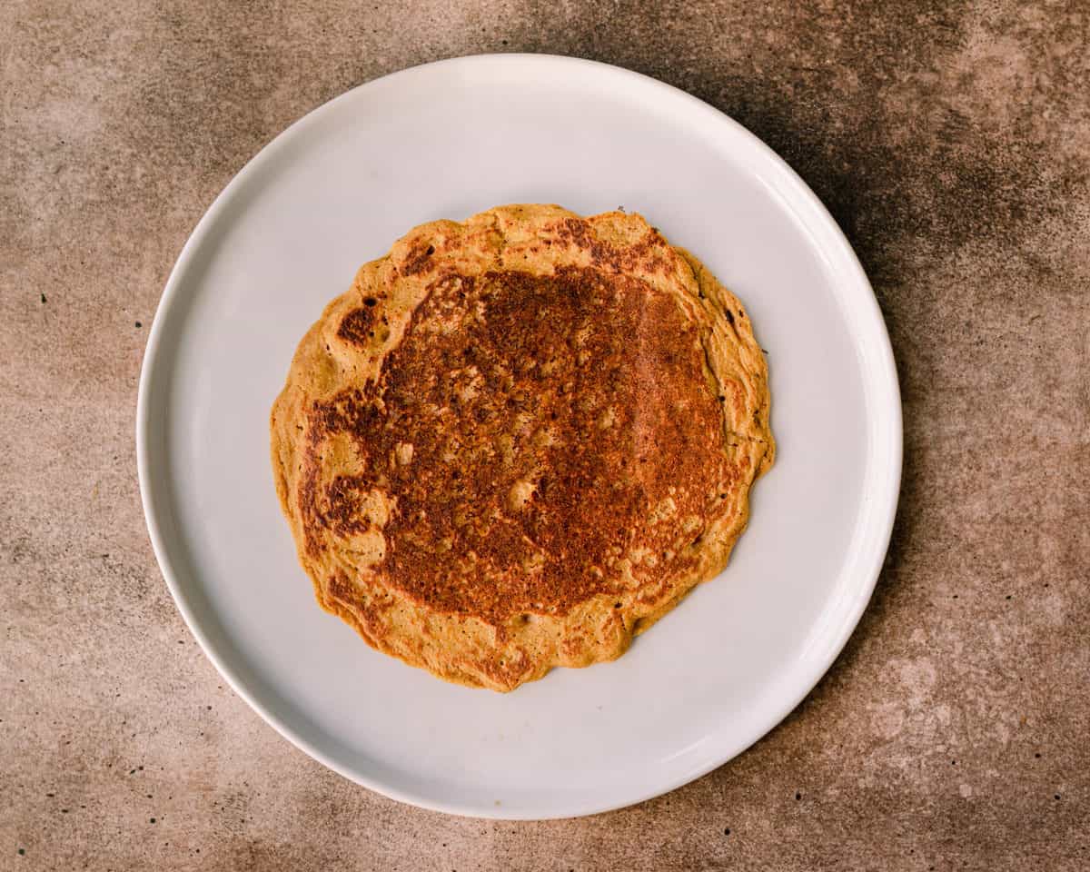 a stack of vegan pumpkin pancakes with raspberries on top